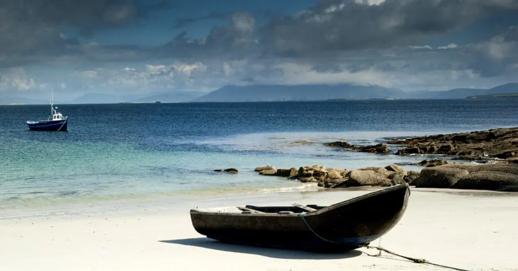 A traditional curragh boat on a white sand beach in Co. Mayo, Ireland