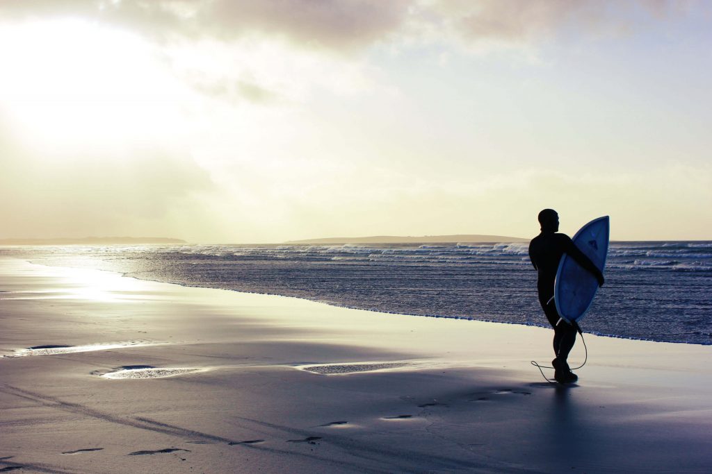 Ein Surfer begutachtet in der Sonne die Wellen in Irland