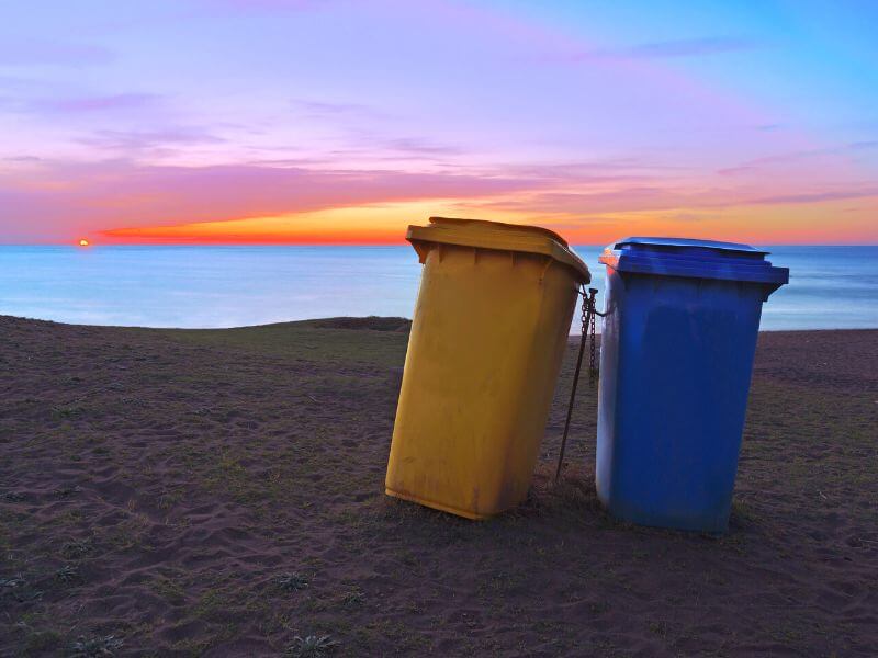 Mülltonnen an einem Strand in Irland bei Sonnenuntergang.