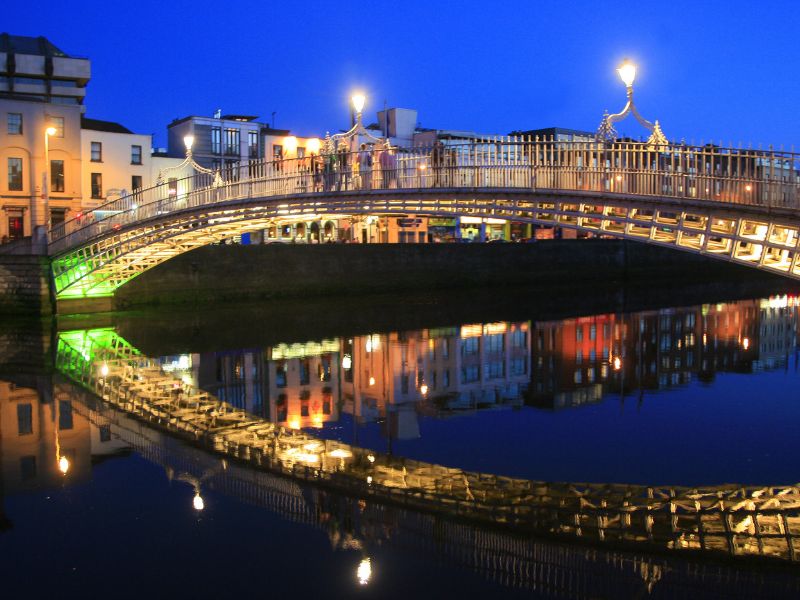 Die Ha'Penny Bridge bei Nacht in Dublin mit schöner Wasserspiegelung