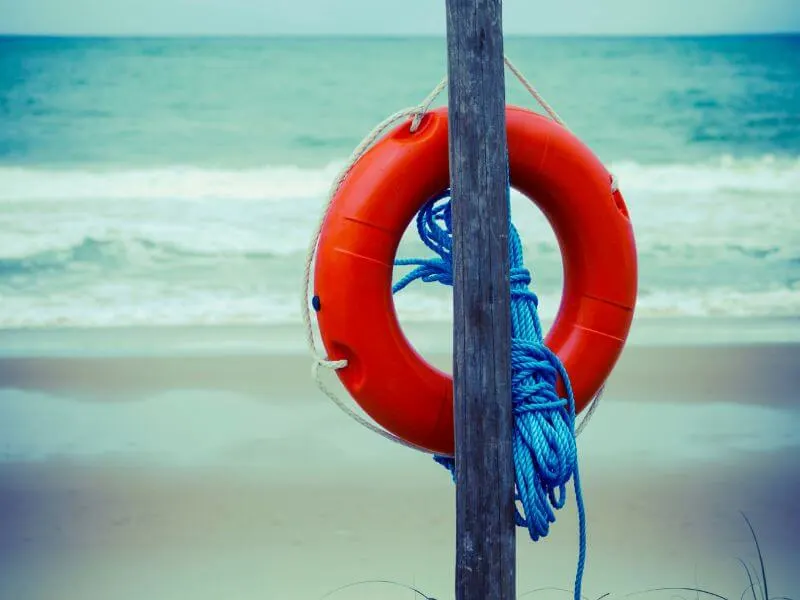 A life ring at a beach with stormy waves in the background.