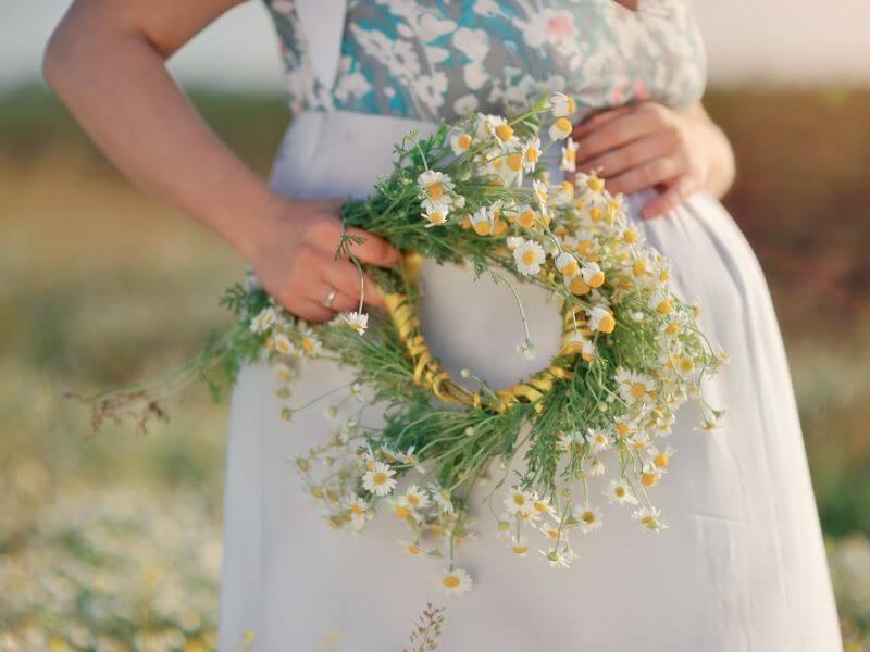 Eine schwangere Frau mit einem Kranz aus Blumen.  