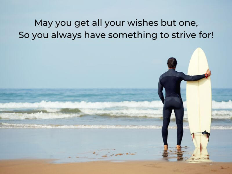 A surfer on a beach waiting for some waves with blessing text.