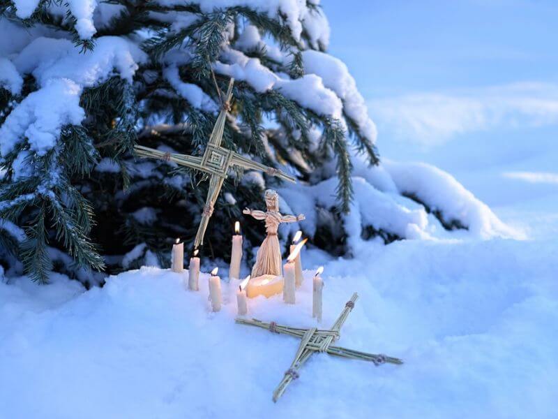 Candles, straw doll and Brigid's crosses in snow marking Imbolc and St. Brigid's day.