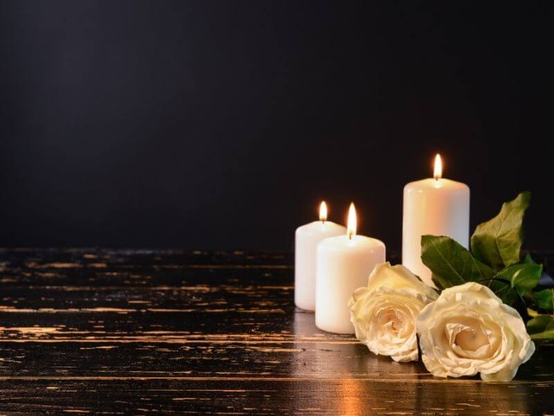 Weiße Rosen und Kerzen auf einem schwarzen Tisch