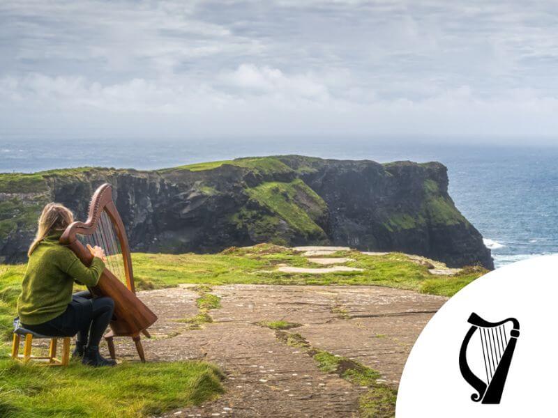 Irisches Harfenmotiv mit einer Harfe spielenden Frau bei den Cliffs of Moher.