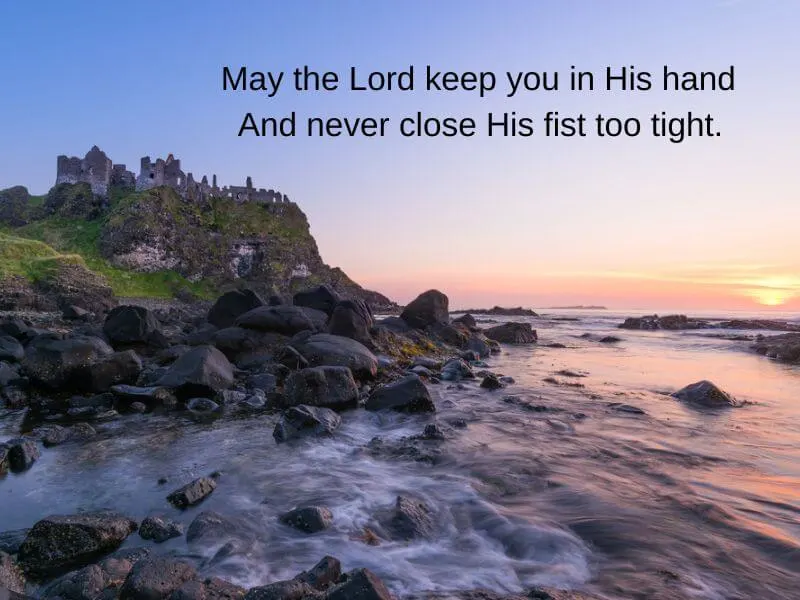 Dramatic coastline at Dunluce Castle in County Antrim with Irish prayer text.