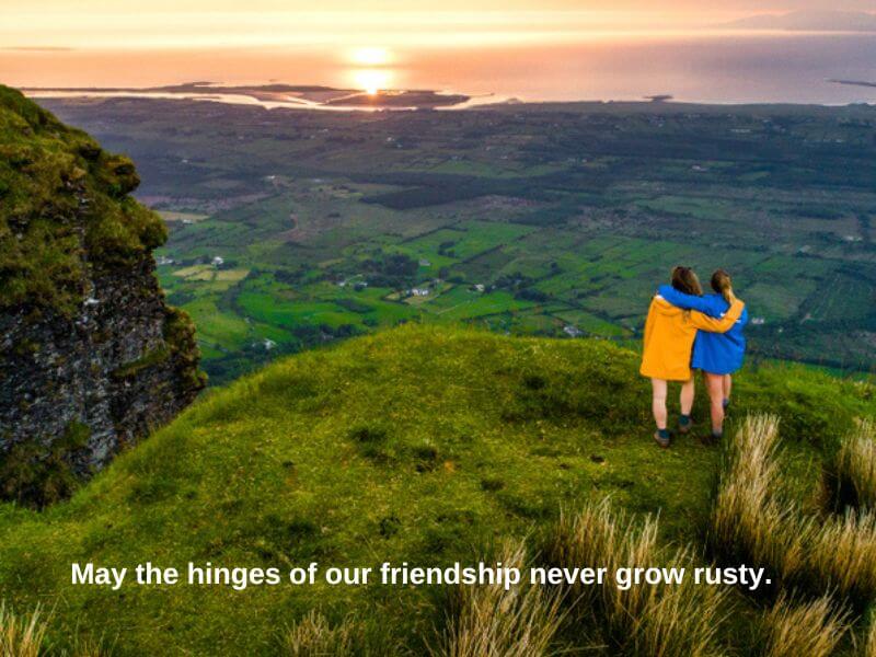 Two friends admiring the view and sunset in Ireland with a friendship blessing.