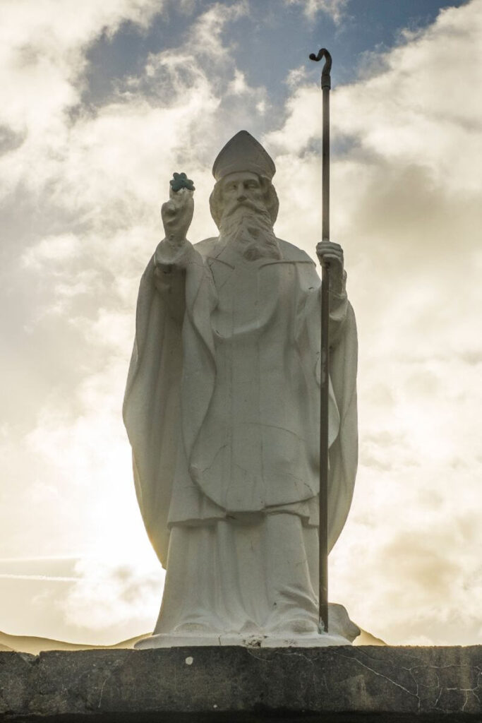 The statue of St. Patrick holding a shamrock at the base of Croagh Patrick Mountain in County Mayo. 