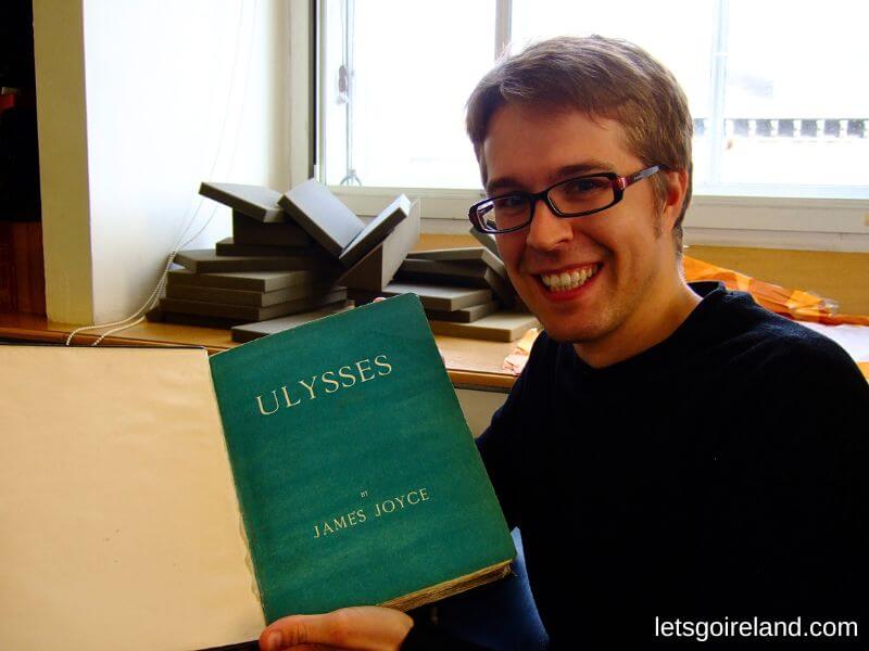 Nils hält eine Erstausgabe von James Joyce' Ulysses im Rare Books Room des Trinity College Dublin.  
